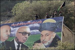 Afghan border police  are seen above a giant poster of Afghanistan's President Hamid Karzai in Torkham on the border of Pakistan, east of Kabul, Afghanistan, Wednesday. At center of poster is Sardar Mohammad Dawood Khan (president 1973-8), and at left Mohammad Zahir Shah, the last King of Afghanistan, reigning for four decades, from 1933 until he was ousted by a coup in 1973.