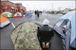 Scott West of Perrysburg, left, and Jamie Adams of Millbury, right, join others camping outside Wednesday at the Chick-Fil-A restaurant in Perrysburg Township.  The restaurant opens Thursday. The first 100 participants who comply with the official rules of a company grand opening promotion receive a grand prize of one Chick-fil-A meal per week for a year. 