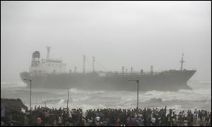 People look at Indian ship Pratibha Cauvery that ran aground with people on board, reportedly due to strong winds on the Bay of Bengal coast in Chennai, India, Wednesday,.