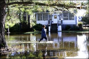Letter carrier Dawn Greco wades in the water to deliver the mail after superstorm Sandy in Crisfield, Md.