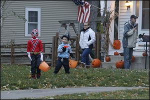 Brothers Vincent Kuhlman, 6, left, and Markus Kuhlman, 4, right, head out to go trick-or-treating on Long St. in Sylvania. Their parents Jennifer Kuhlman, and Andrew Kuhlman, follow.