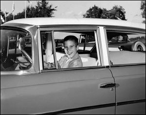 This 1957 photo shows 10-year-old Mitt Romney in Detroit behind the wheel of a Nash automobile, manufactured by American Motors Corp.
