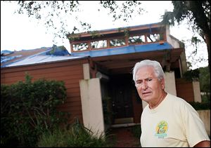 Richard Campanaro stands in front of an empty townshome in Cranes Roost Villas in Altamonte Springs, Fla. Mr. Campanaro says the home is a foreclosure that Bank of America has allowed to fall into disrepair. By slowly releasing their properties, some lenders can benefit from rising home values.
