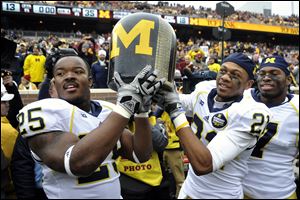 From left, Michigan's Kenny Demens, Roy Roundtree and Brandin Hawthorne carry the 