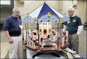 Norville Cramer of Hillsdale, Mich., left, views wooden horses and a rotating carousel made by Don Brewer of Toledo’s Old West End, right, during an exhibit of works by the Black Swamp Woodcarvers at the St. Clement Community Center in Toledo. Members of the woodcarvers club range from beginners to those with many years of experience, and the exhibit Sunday displayed a variety of wood-carving techniques. 