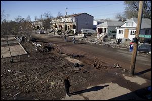 Maryann Eger, bottom, looks over the destruction in her neighborhood of New Dorp in the Staten Island borough of New York, Sunday, in the aftermath of Superstorm Sandy. 