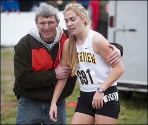 Sylvania Northview runner Robin Foster is helped by a race volunteer after finishing the Girls Div. I State High School Cross Country Championship, at National Trail Raceway in Hebron, Ohio.