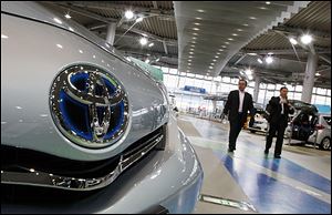 A couple walk by Lexus models displayed at a Toyota Motor Corp. showroom in Tokyo. Toyota's quarterly profit tripled, driven by a recovery from natural disasters, and the company raised its full-year earnings forecast despite a sales slump in China. 