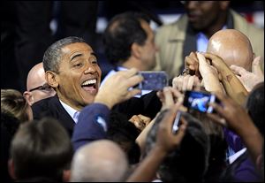 President Barack Obama smiles for cameras as he shakes hands with supporters after speaking at a campaign event at Nationwide Arena Monday, Nov. 5, 2012, in Columbus, Ohio.