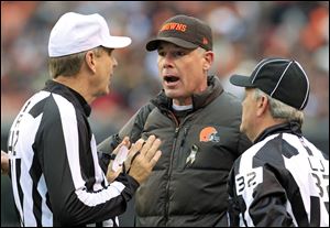 Cleveland Browns head coach Pat Shurmur, center, argues a call with referee Jeff Triplette, left, and line judge Jeff Bergman in the first quarter of an NFL football game against the Baltimore Ravens.