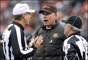 Cleveland Browns head coach Pat Shurmur, center, argues a call with referee Jeff Triplette, left, and line judge Jeff Bergman in the first quarter of an NFL football game against the Baltimore Ravens, Sunday, Nov. 4, 2012, in Cleveland. (AP Photo/Tony Dejak)