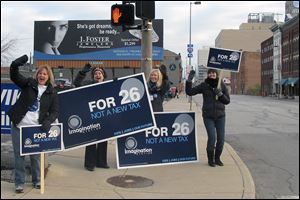 Employees of Imagination Station encourage a 'yes' vote from the morning commuters in downtown Toledo on the corner of Erie and Washington Streets today.