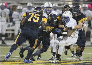 Jacob LaPoint (90) and Jack Linch (44) tackle Findlay's Vance Settlemire as Joenathan Mays moves in. Whitmer has allowed just 6.8 points per game.