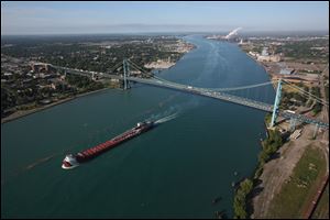 A freighter passes the Ambassador Bridge that links Detroit on the right and Windsor on the left. A new Canadian-financed bridge linking the cities could create thousands of jobs.