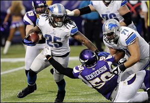 The Lions' Mikel Leshoure (25) gets a block from teammate Riley Reiff, right, as he tries to break a tackle by the Vikings' Erin Henderson, center, during the first half.
