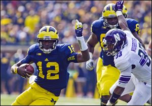 Michigan quarterback Devin Gardner tries to evade Northwestern linebacker David Nwabuisi.
