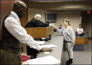 Holly Most  shakes hands with Judge Brian MacKenzie, while Mike McGlown, probation officer, stands by at a session of  Veterans Court in Novi, Mich.