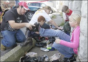 Jeremy Schmidlin of Toledo helps his niece Hannah Jeski, 9, also of Toledo, check the size of a pair of boots. Hundreds of people wait patiently for their chance to get a used pair of shoes at the South Toledo Community Center. 
