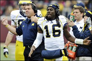 Michigan head coach Brady Hoke, left, and quarterback Denard Robinson, right, call over the offense during a timeout in the third quarter of an NCAA college football game against Minnesota, Saturday, Nov. 3, 2012, in Minneapolis. Robinson did not play because of an undisclosed injury.