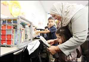 Khadiga Al-Jabri reads to Lena Balaa and Zachary Sayed after Books 4 Buddies donated materials to replace those lost in a recent arson at the Islamic Center of Greater Toledo.