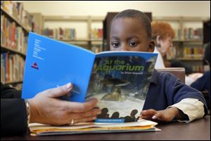 Ke’Mon Anderson shares a book about life at an aquarium with a tutor in the library of Pickett Elementary School. He is part of  the ‘Creating Young Readers’ program.