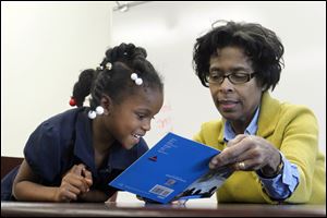 Volunteer reader Doris Whatley and Kanijah Edwards read in the library of Pickett Elementary School. They are using a technique in which they take turns reading a book.