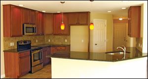 Dark brown maple cabinetry with a chocolate glaze finish shines in the home's kitchen; a tile back-splash with glass inserts glimmers among the stainless steel appliances.