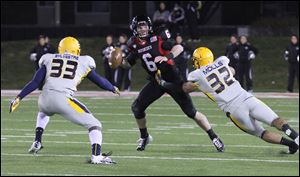 Toledo’s Junior Sylvestre, left, and Dan Molls, right, pressure Northern Illinois quarterback Jordan Lynch, who threw for 407 yards and rushed for 162. 