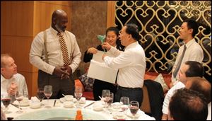 His Chinese hosts accept a glass flower — made by northwest Ohio artist Larry Mack — from Toledo Mayor Mike Bell on Wednesday in Shenzhen, China.