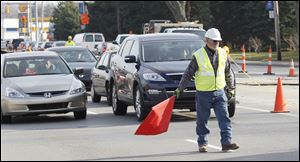 A worker stops traffic due to gas line construction Thursday on Monroe Street, between Secor Road and Sylvania Avenue.