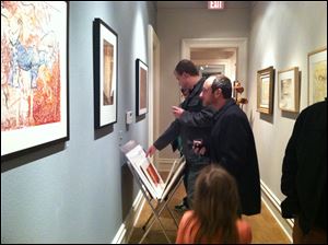 Luke Kende, of Memphis, Tenn., foreground, looks at some of the artwork done by his father, Ivan Kende, of Toledo, in the 
