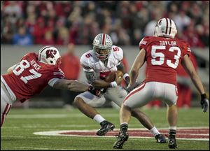 Ohio State quarterback Braxton Miller, center, scrambles between Wisconsin's Ethan Hemer, left, and Mike Taylor during the second half Saturday in Madison, Wis. The Buckeyes won 21-14 in overtime, and now they could complete a 12-0 regular season this week against Michigan.