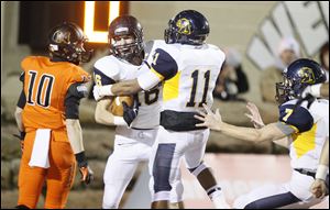 Whitmer's Keith Howell, 16, Me'Gail Frisch, 11, and Nick Holley, 7, celebrate after Howell recovered a fumble in the end zone for a touchdown during the first quarter.