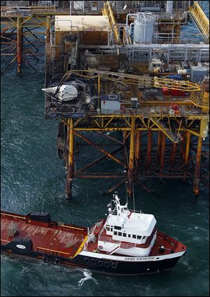 In this aerial photograph, a supply vessel moves near an oil rig damaged by an explosion and fire in the Gulf of Mexico about 25 miles southeast of Grand Isle, La. Four people were transported to a hospital with critical burns; one of them was upgraded Sunday to fair condition. Two remained in critical condition and one in serious condition, doctors say.