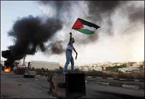A Palestinian waves the national flag during a protest against Israel’s airstrikes in Gaza.