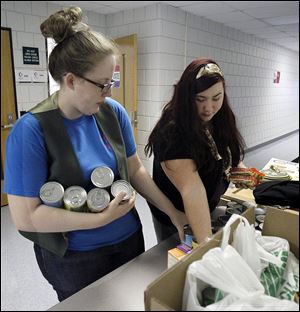 Christina Perry, 24, left, and Stacey Field, right, help stock canned goods and non-perishable food collected during the 
