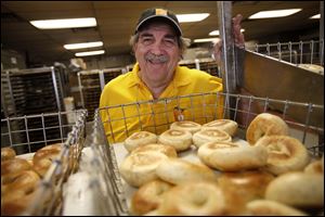 Barry Greenblatt, 63, owner of Barry Bagels, offers his signature smile over an assortment of bagels at his  Sylvania store. Mr. Greenblatt has been making bagels since 1972.