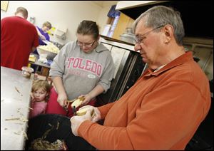 Dave Luce, right, and Lisa Hall, with daughter Baileigh Hall, 2,  peel potatoes at Pilgrim Church in Toledo in preparation for a Thanksgiving dinner that expects to feed upward of 400 people.