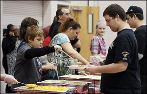 Volunteer Noah Power, 11, serves food to Ryan Kinnison of Northwood during a Thanksgiving dinner sponsored by House of Bread Ministries Inc. at  Bethlehem Baptist New Life Center.