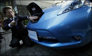A Nissan employee demonstrates the electric recharge plug-in process for the company's latest Leaf. Plans for U.S. sales of the vehicle have not been detailed.