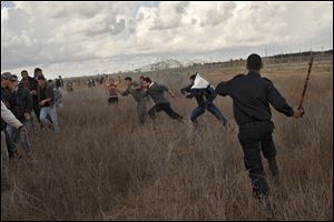 A Hamas police officer prevents Palestinians to approach Friday near the Israeli Gaza border fence. Hundreds of Gaza crowds surged toward Israel's border fence with the Hamas-ruled territory, in a no-go-zone. Many in the crowd were returning to their farm land after the cease fire.