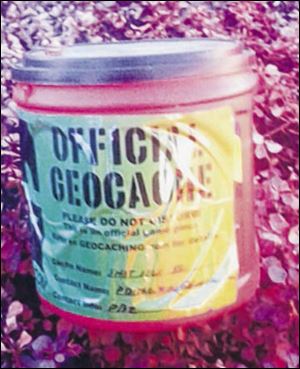 A coffee can is marked as  a geocache and hidden under bushes.