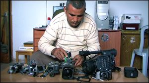 Co-director Emad Burnat displays his five broken cameras, from the documentary ‘5 Broken Cameras.’
