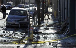 People walk in a damaged area about a block away from the site of a Friday-evening gas explosion that leveled a strip club in Springfield, Mass.The blast, which injured 18 people and damaged 42 buildings, was blamed Sunday on a utility worker who accidentally punctured a high-pressure pipeline while looking for a leak.