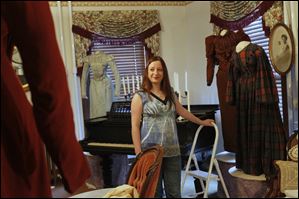 Period dresses surround curator Holly Hartlerode as she sets up a Victorian-era parlor for the holiday tour. The event, which annually attracts more than 1,000 visitors, is scheduled Dec.8-21. 
