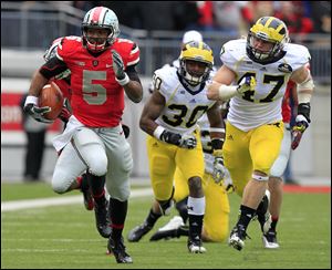 Ohio State quarterback Braxton Miller, left, breaks away from Michigan defenders Thomas Gordon, center, and Jake Ryan during the third quarter of an NCAA college football game in Columbus, Ohio. Ohio State beat Michigan 26-21.