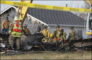 Fire officials use a front end loader to sift through the rubble after a fatal fire.