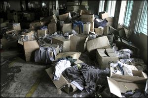 Boxes of garments are piled near equipment charred in the fire that killed 112 workers Saturday at the Tazreen Fashions Ltd. factory, on the outskirts of Dhaha, Bangladesh. Some of the major retailers said the merchandise was being produced without their approval.