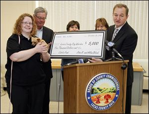 Dave Murray, managing editor of the Blade, right, presents a $5,000 check, on behalf of John Robinson Block and Allan Block of Block Communications Inc., parent company of The Blade, to Lucas County Dog Warden Julie Lyle for Cutie's fund. Cutie, the dog, is being held by Ms. Lyle.