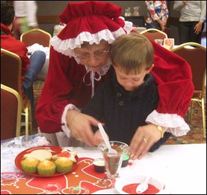 Mrs. Claus helps a little one decorate cupcakes at the Osthoff Resort.
